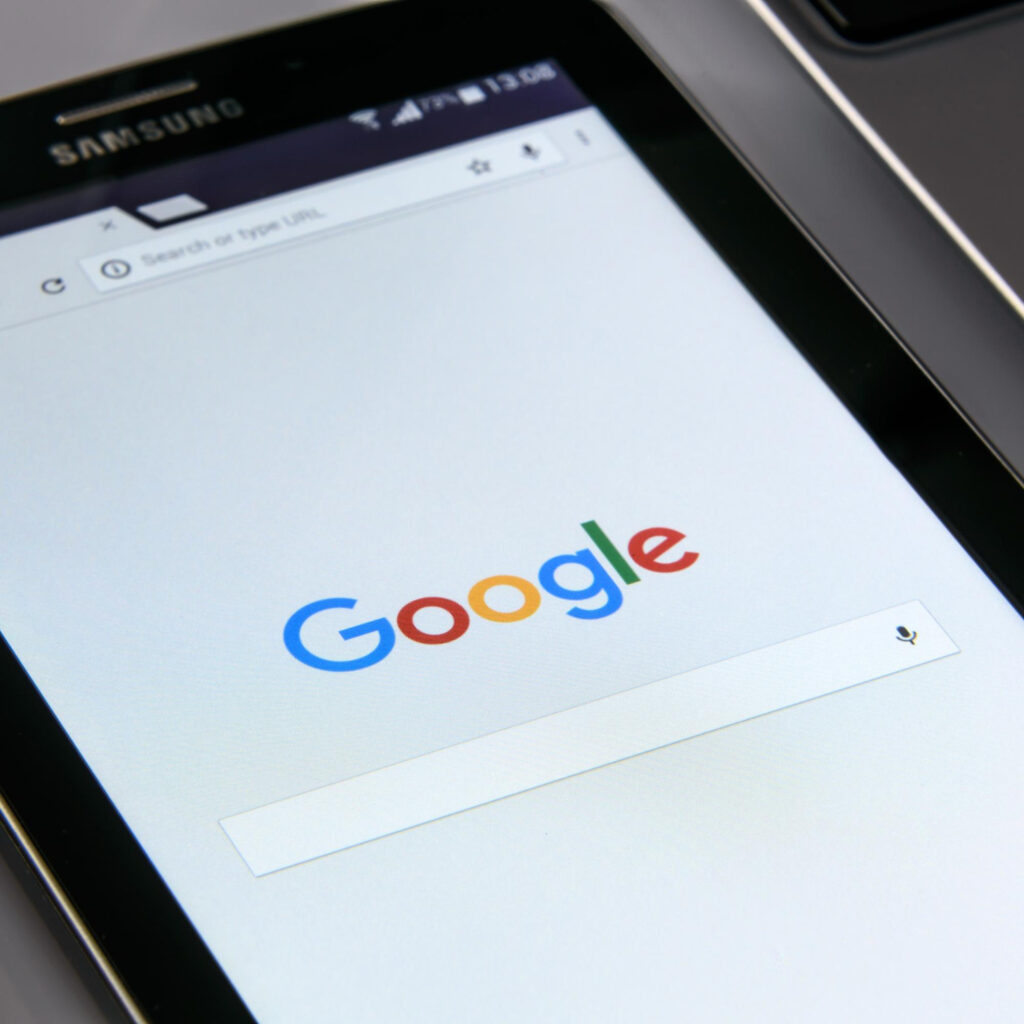 Kuvassa puhelin pöydällä, jossa auki Googlen etusivu.