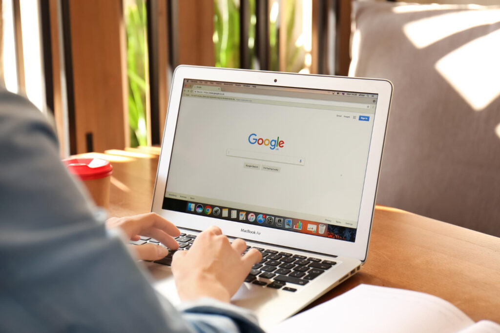 Nainen istumassa tietokone sylissä tutkimassa orgaanista näkyvyyttä Googlessa.